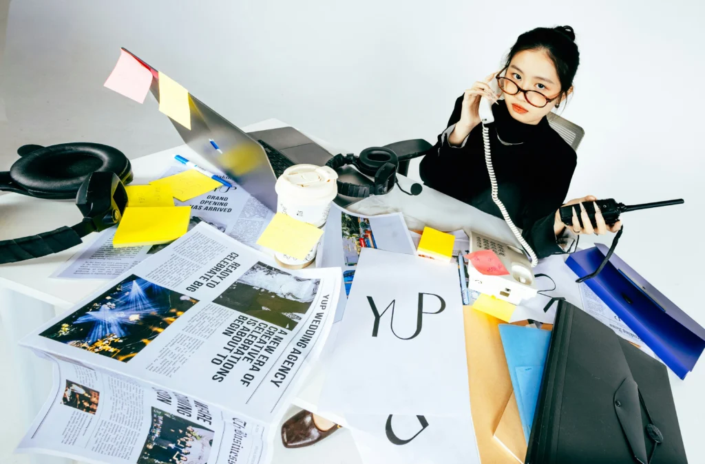 Entrepreneur sitting at a busy desk surrounded by work materials