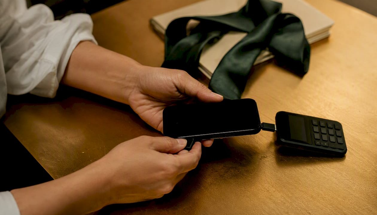 Hands connecting smartphone and card reader on desk